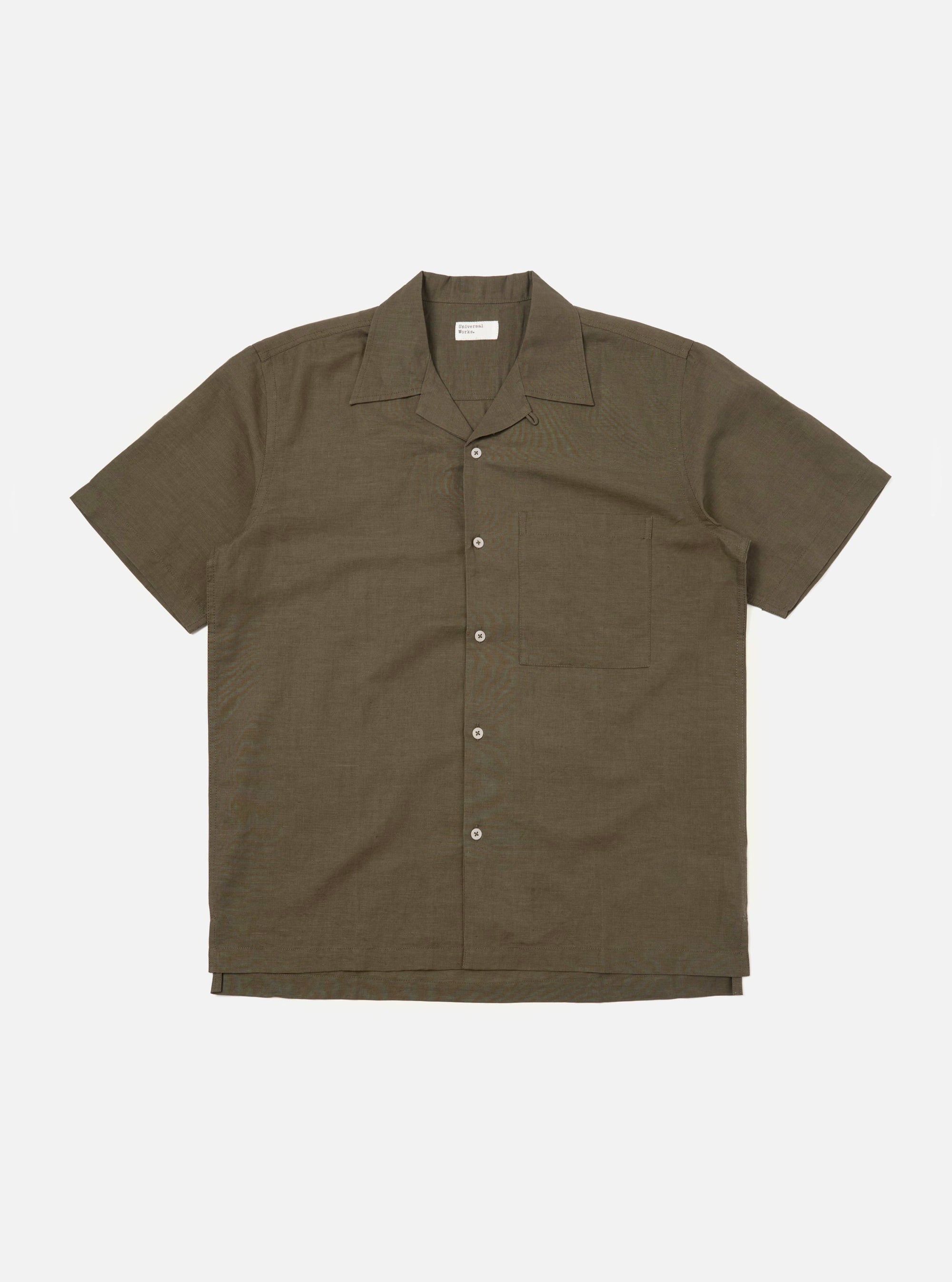An Olive Linen Cotton Shirting Camp Shirt is displayed flat against a plain white background. The shirt features a relaxed fit with a one-piece camp collar, a full button-down front, and a single large patch pocket on the left chest. The short-sleeved garment is shown in a muted olive green color with a visible textured slub weave.