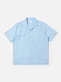 The Pale Blue Linen Cotton Shirting Camp Shirt is displayed flat against a plain white background. The shirt features short sleeves, a relaxed camp collar, and a single large chest pocket on the left side. It has a button-down front and a straight hem with small side splits.