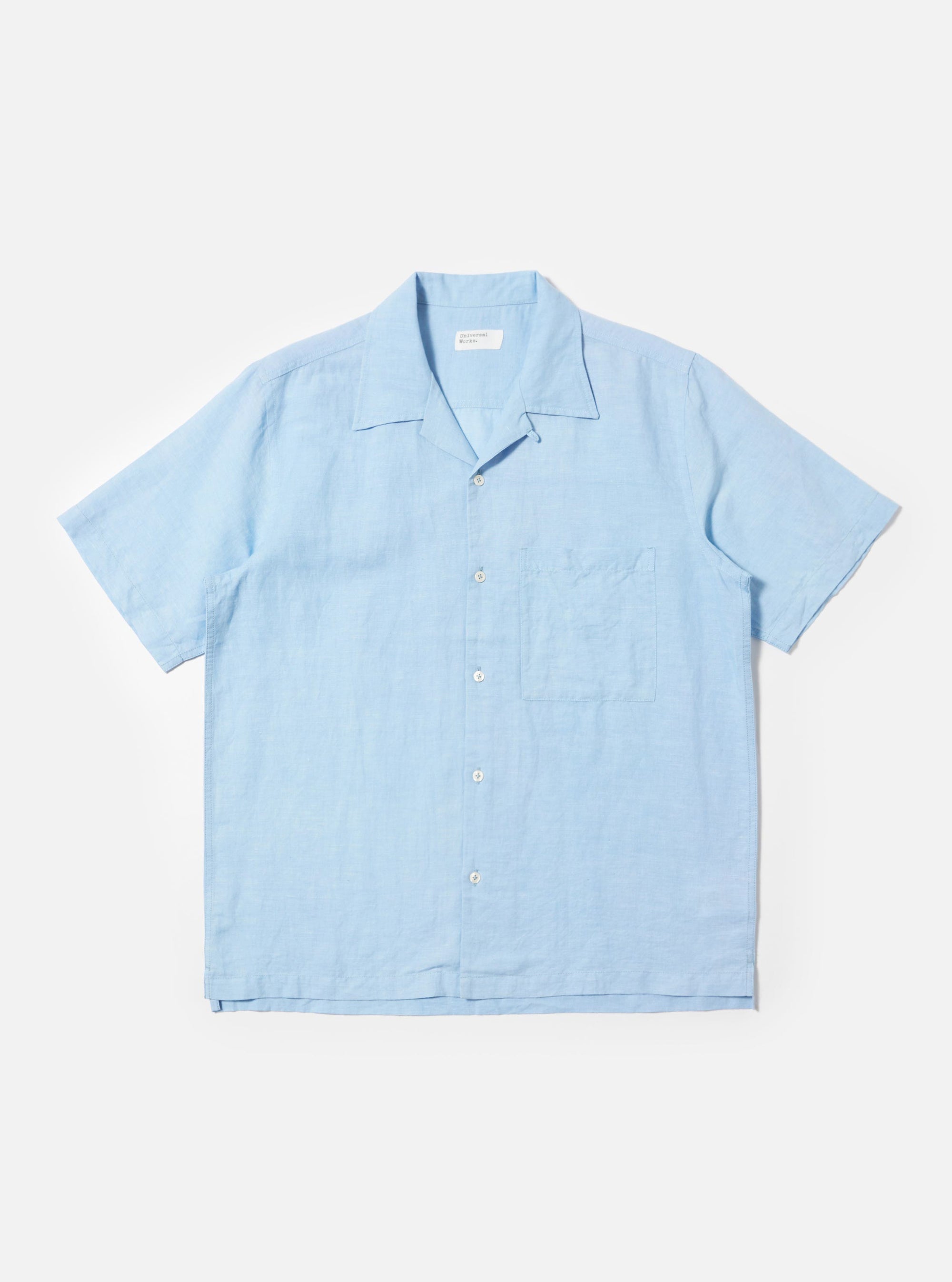 The Pale Blue Linen Cotton Shirting Camp Shirt is displayed flat against a plain white background. The shirt features short sleeves, a relaxed camp collar, and a single large chest pocket on the left side. It has a button-down front and a straight hem with small side splits.
