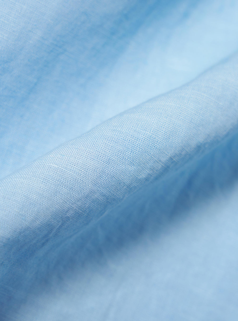 A detailed, close-up fabric swatch of the Pale Blue Linen Cotton Shirting Camp Shirt. The image highlights the textured, slubbed weave of the light blue material, showing the fine intersection of linen and cotton threads.