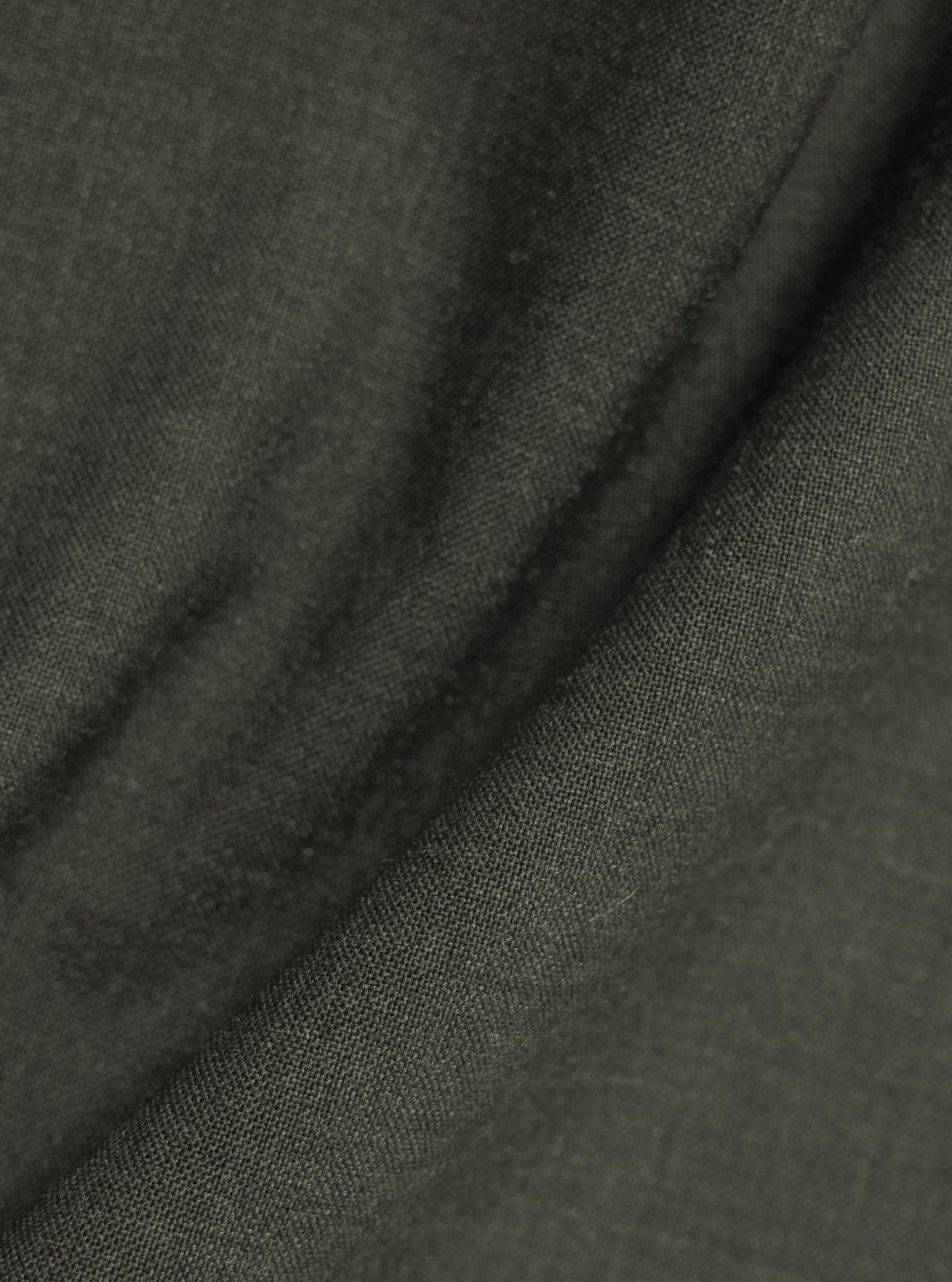 A detailed close-up fabric swatch of the Olive Marl Tropical Suiting Ewan Shirt. The image highlights the textured olive green marl weave and the fine detail of the polyester and wool blend material.