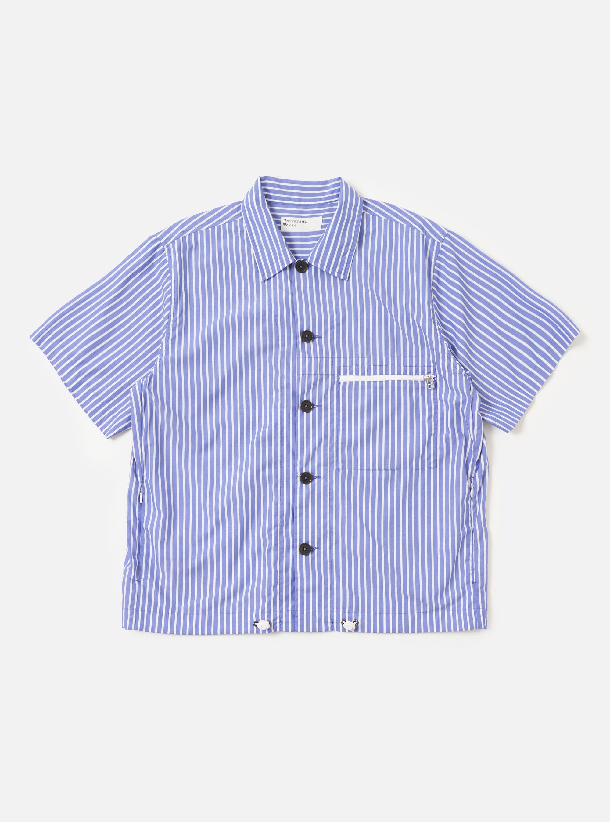 The Blue/White Cotton Stripe Z Tech Overshirt is shown laid flat against a solid white background. The garment features a vertical blue and white stripe pattern, a classic pointed collar, and a full button-down front. A single vertical zipped pocket is prominent on the left chest. The overshirt has long sleeves with elasticated cuffs and an elasticated drawcord hem.