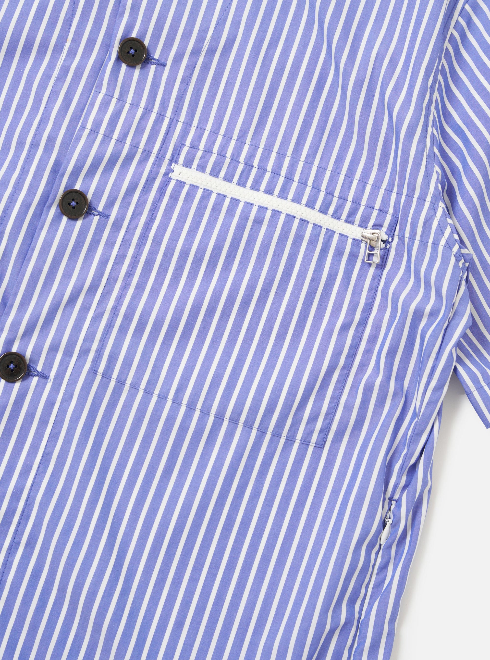 The Blue/White Cotton Stripe Z Tech Overshirt is shown from the back, displayed flat against a plain white background. The image highlights the horizontal back yoke with a central box pleat, short sleeves, and a straight hem. The garment features a thin blue and white vertical stripe pattern throughout.