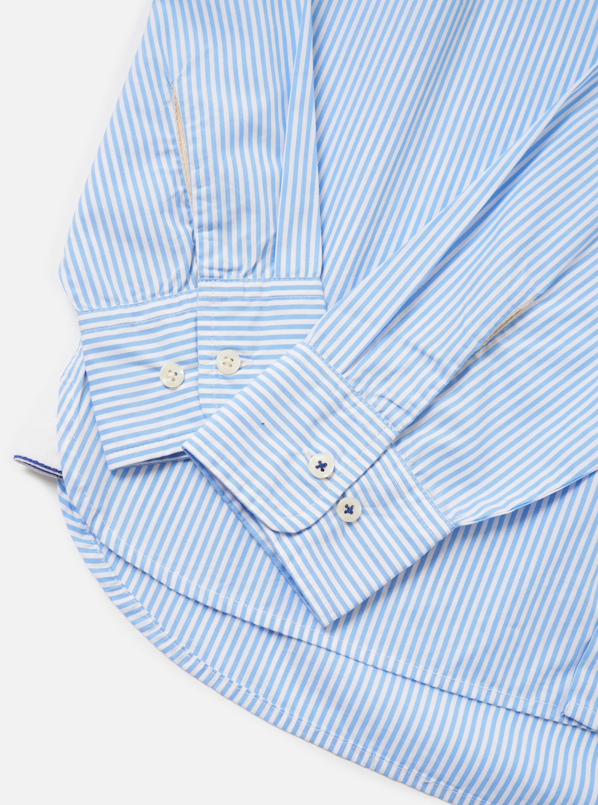 The Sky/White Classic Nipon Stripe Lazy Day Shirt is shown from the back, laid flat against a solid white background. The garment features thin light blue and white vertical stripes. Key details include a horizontal back yoke and a central box pleat that adds volume to the relaxed silhouette.