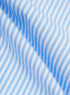 A close-up fabric swatch of the Sky/White Classic Nipon Stripe Lazy Day Shirt displays a vertical stripe pattern in sky blue and white. The image highlights the texture of the cotton material and the varying widths of the stripes.
