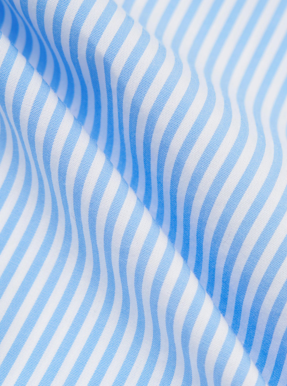A close-up fabric swatch of the Sky/White Classic Nipon Stripe Lazy Day Shirt displays a vertical stripe pattern in sky blue and white. The image highlights the texture of the cotton material and the varying widths of the stripes.