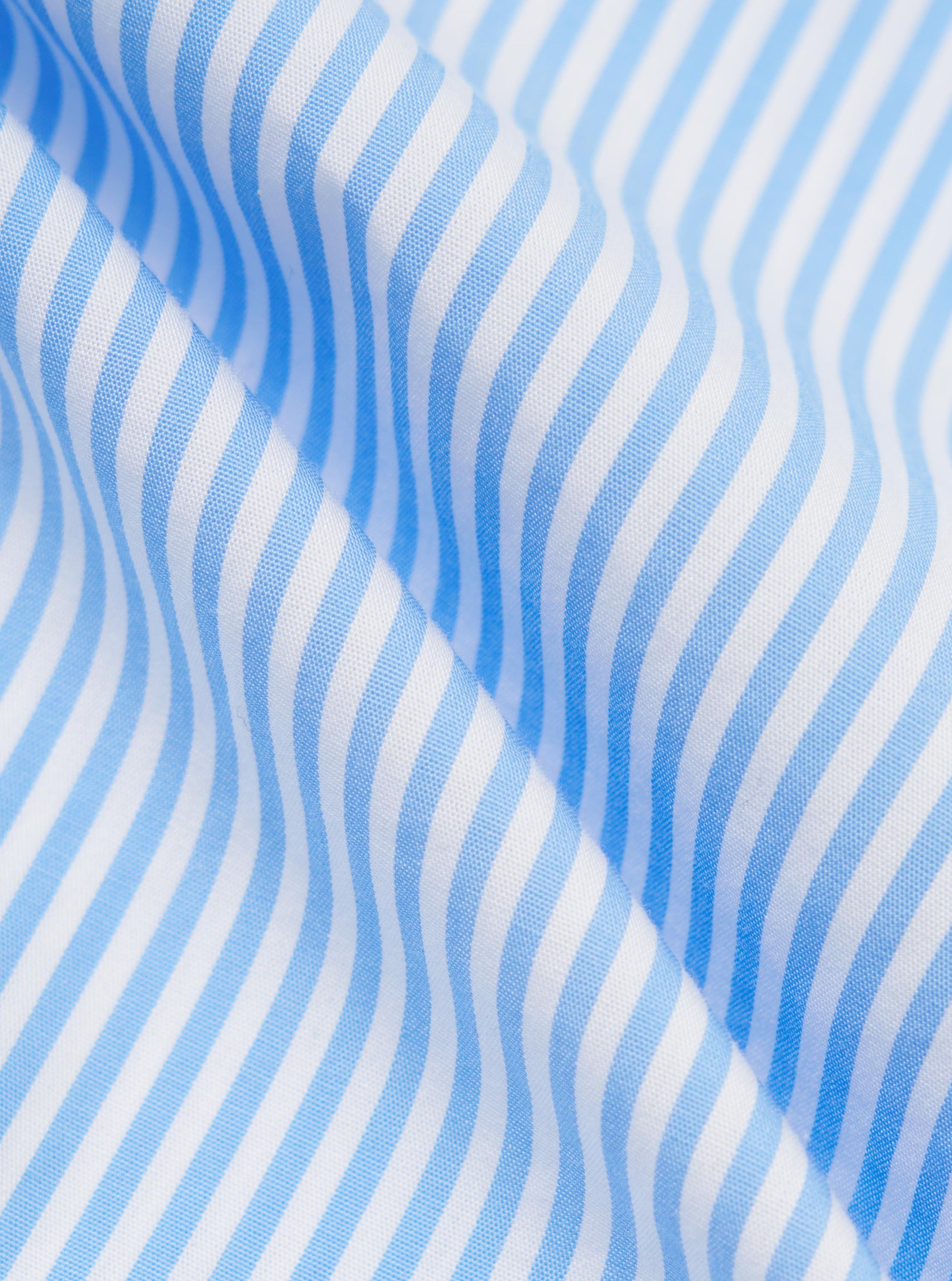 A close-up fabric swatch of the Sky/White Classic Nipon Stripe Lazy Day Shirt displays a vertical stripe pattern in sky blue and white. The image highlights the texture of the cotton material and the varying widths of the stripes.