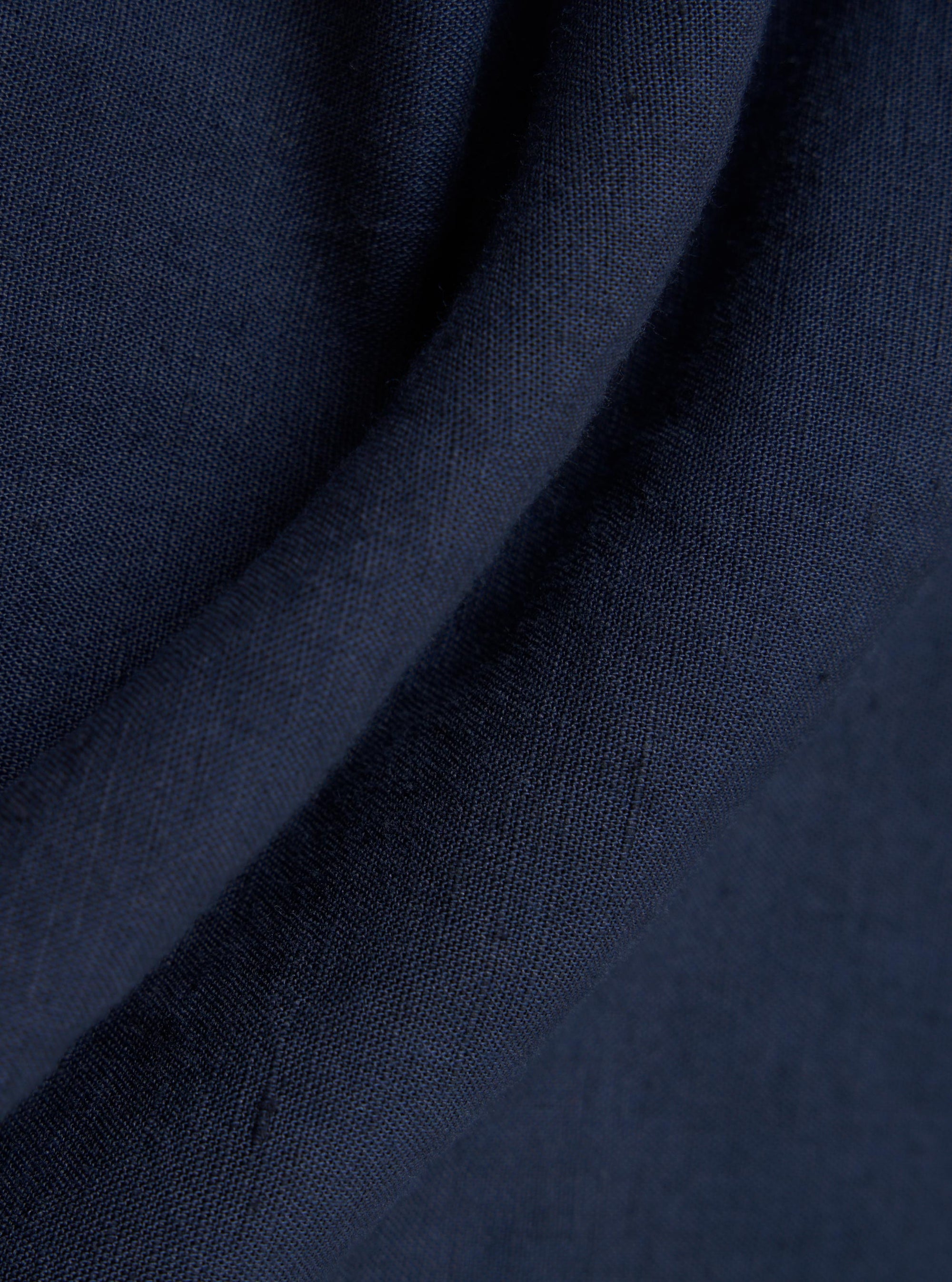 A detailed, close-up fabric swatch of the Navy Linen Cotton Shirting Bakers Overshirt displays a dark navy blue textile with a visible, textured weave pattern. The fabric is shown flat and fills the frame.