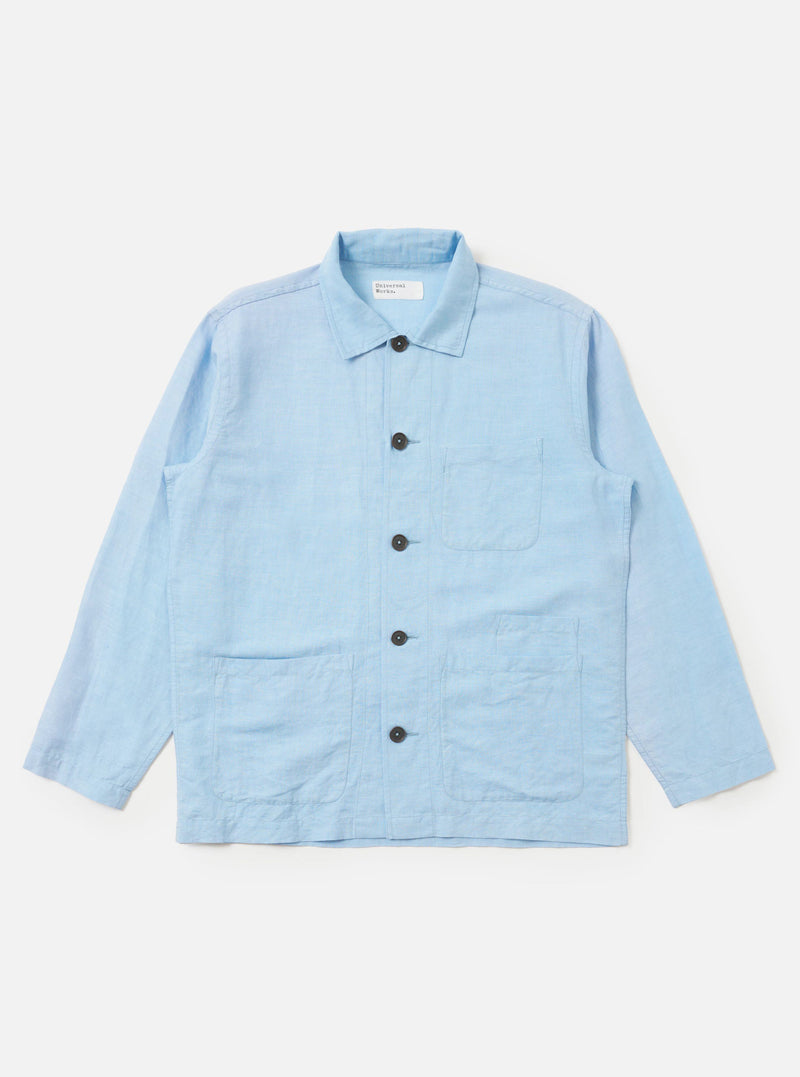 A Pale Blue Linen Cotton Shirting Bakers Overshirt is shown laid flat against a solid white background. The garment features a classic pointed collar, a full button-down front, one asymmetric chest pocket, and two large patch pockets at the waist. The light blue fabric has a subtle, textured appearance.