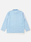 The Pale Blue Linen Cotton Shirting Bakers Overshirt is shown from the back, displayed flat against a plain white background. The image highlights the horizontal back yoke, simple one-piece collar, and the straight hem of the garment. The fabric is a light blue linen-cotton blend.