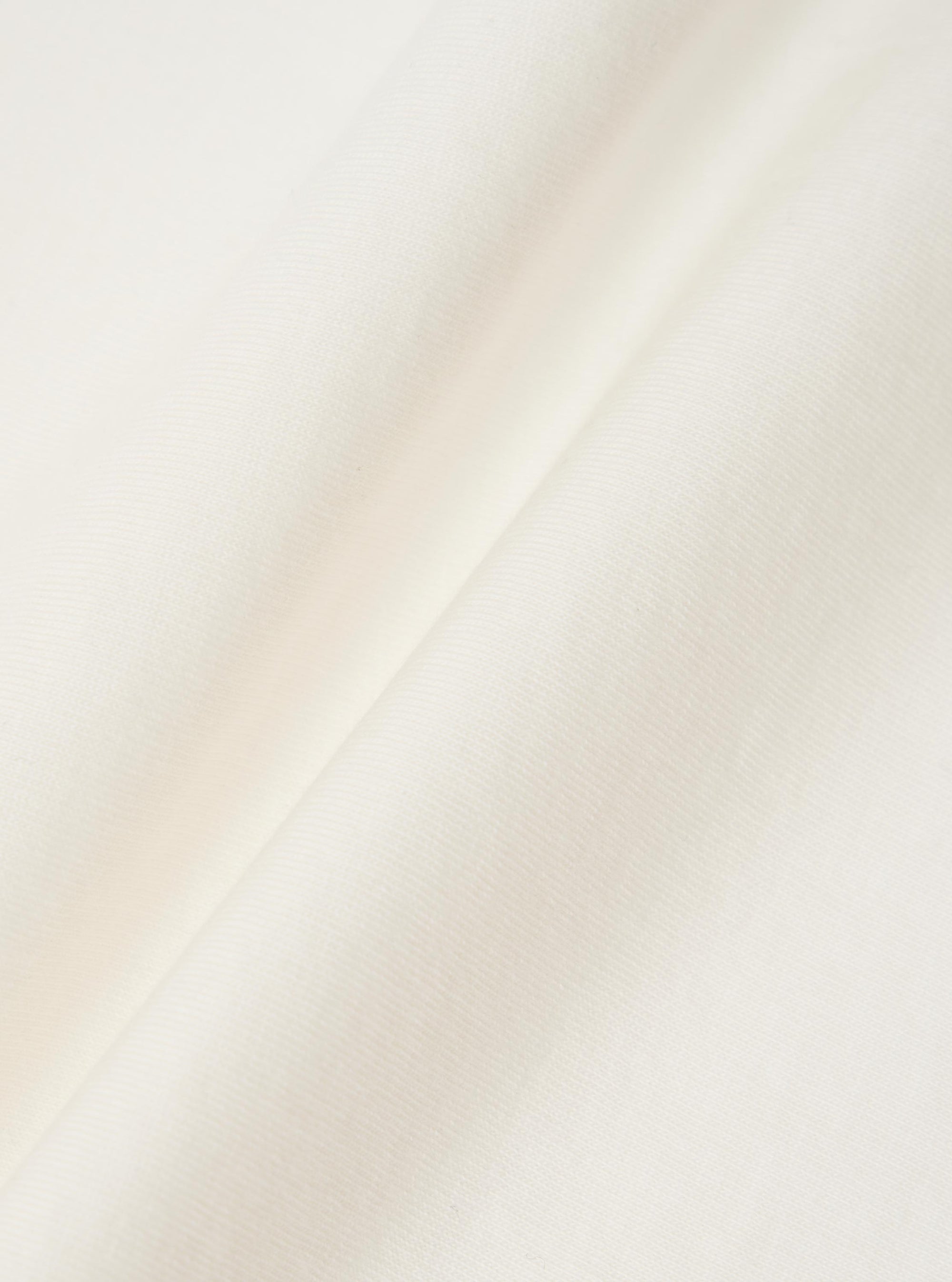 A close-up fabric swatch of the Ecru Single Jersey Wish Wish You Were Here Tee. The image highlights the textured, cream-colored cotton jersey material, showing the fine knit and soft surface of the fabric.