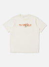 The Ecru Single Jersey Trail Trail To Hotel Delux Tee is shown laid flat against a solid white background. The short-sleeved t-shirt features a classic ribbed crew neck and a small graphic print on the left chest.