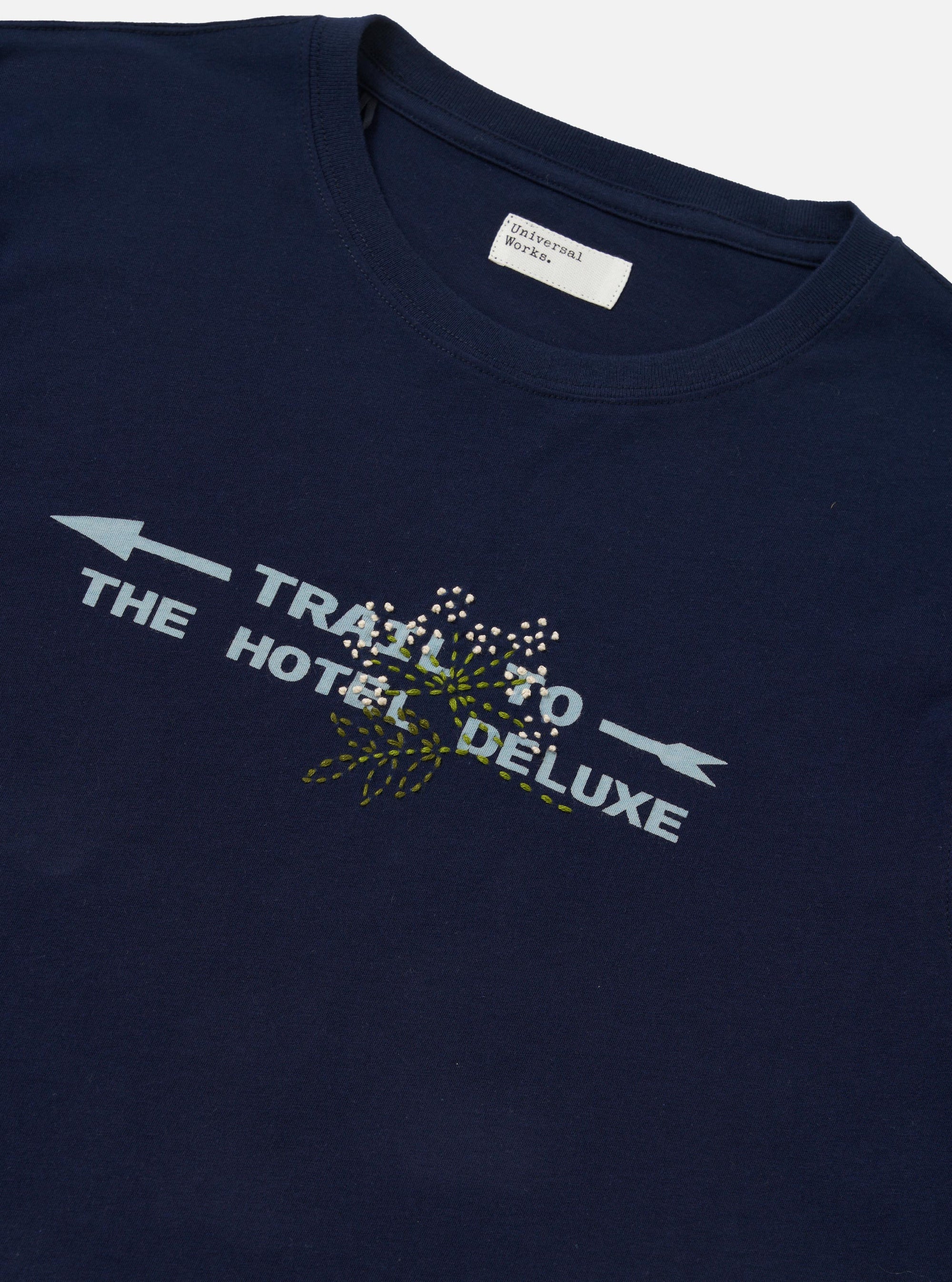 The Navy Single Jersey Trail Trail To Hotel Delux Tee is shown from the back, laid flat against a plain white background. The navy blue t-shirt features a classic crew neck, short sleeves, and a straight hem.
