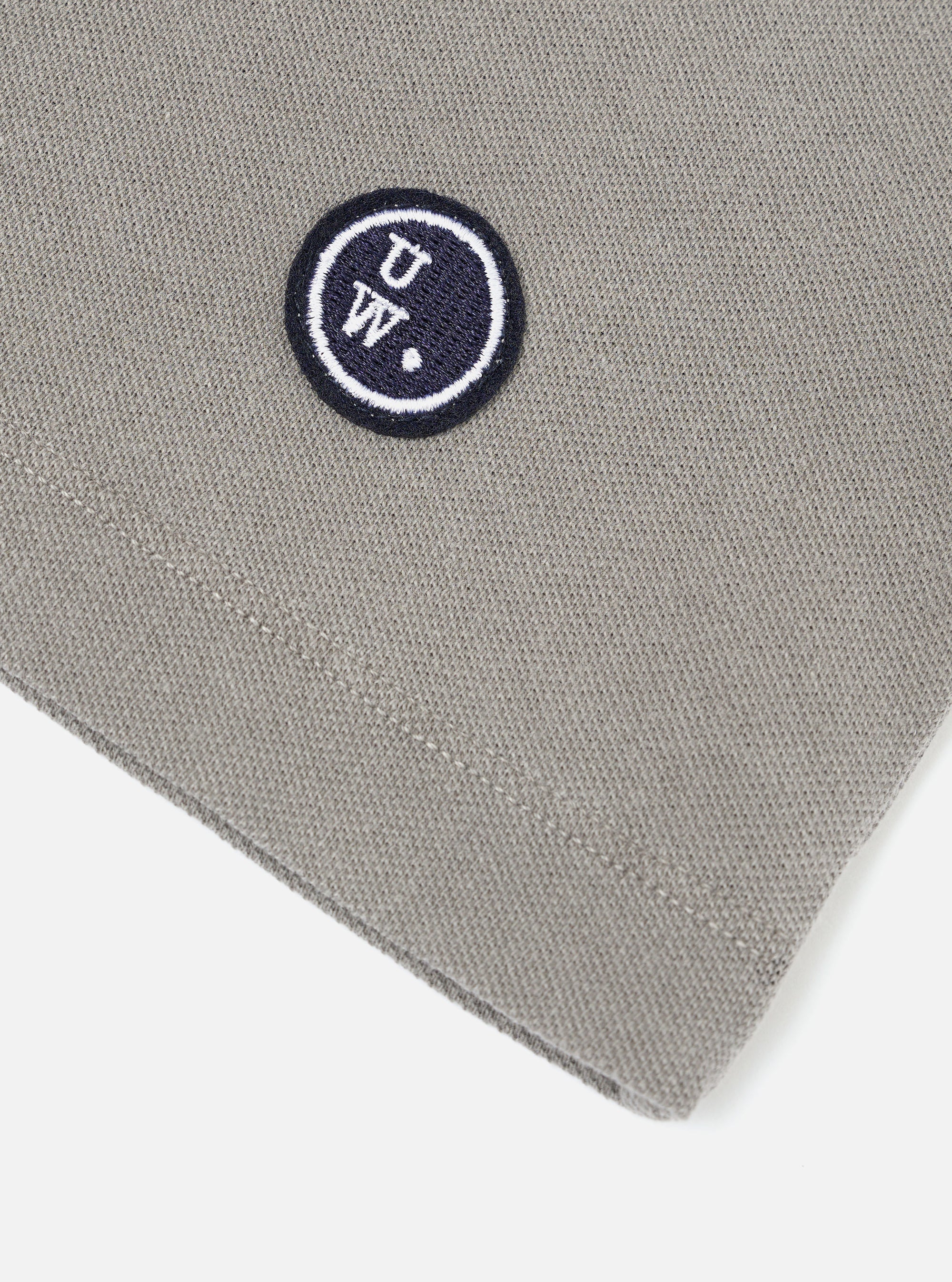 A mid grey piquet core tee is shown from the back, laid flat against a solid white background. The image highlights the short sleeves, a straight hem, and a simple crew neck with a self-bound finish.