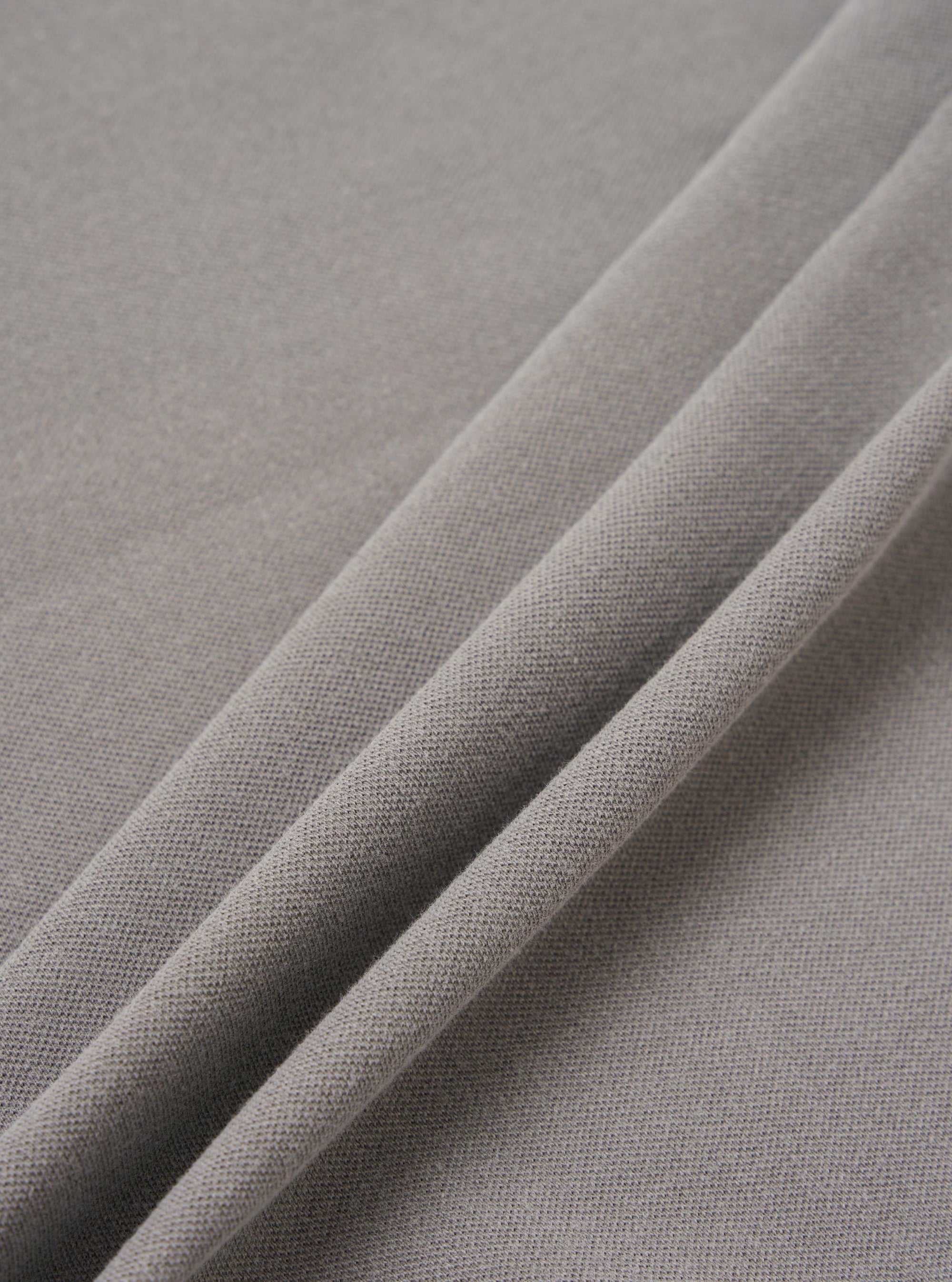 A close-up fabric swatch of the Mid Grey Piquet Core Tee shows the detailed texture of the mid-grey cotton piquet material. The image focuses on the fine, honeycomb-like weave of the knit fabric against a neutral background.