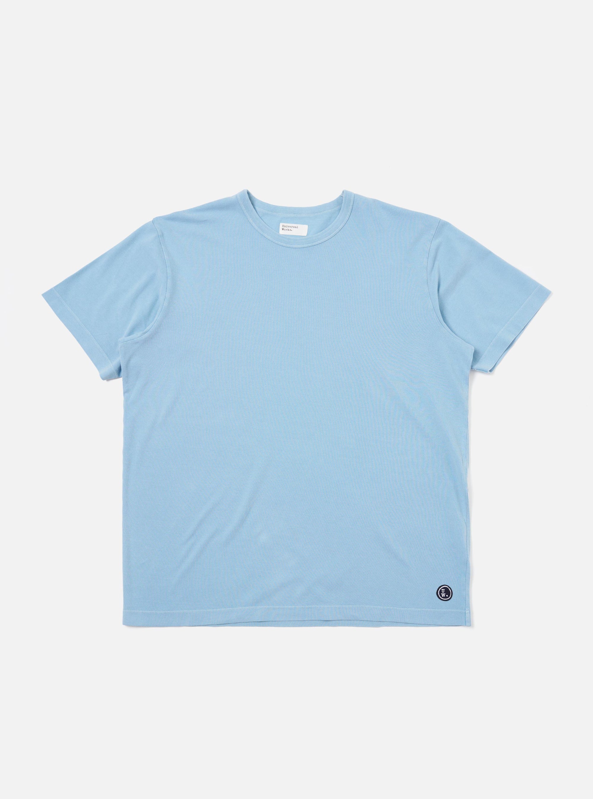 The Pale Blue Piquet Core Tee is shown laid flat against a plain white background. The short-sleeve t-shirt features a classic crew neck with a self-bound collar and a clean, regular-fit silhouette.
