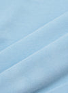 A close-up, square fabric swatch of the Pale Blue Piquet Core Tee highlights the detailed texture of the cotton piquet weave. The image captures the consistent, small-scale geometric pattern of the pale blue fabric.
