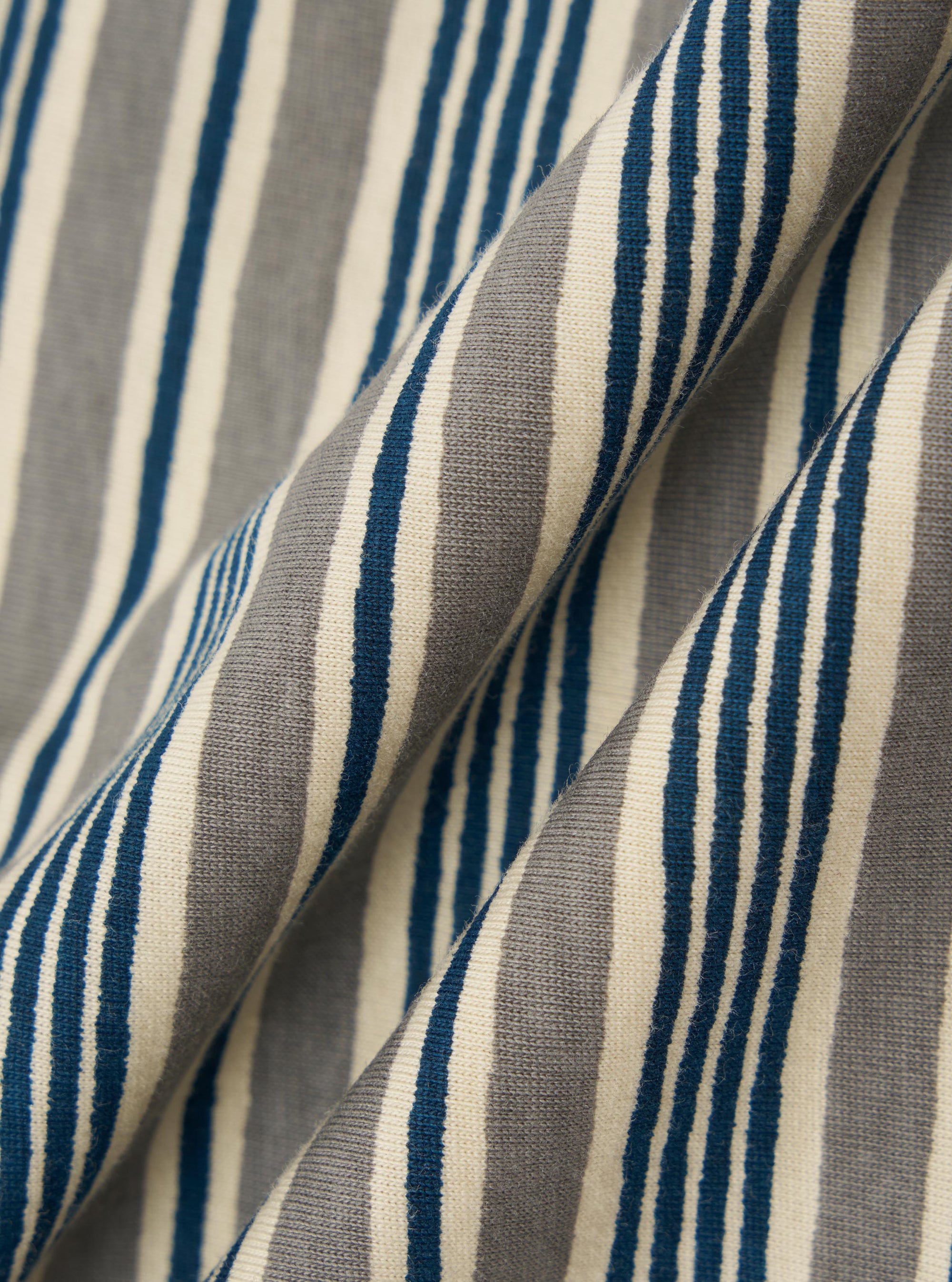 A square fabric swatch of the Grey OS Stripe Jersey Core Tee features a detailed close-up of a pale grey and white horizontal striped pattern. The fabric has a soft, irregular character with a lightweight jersey texture.