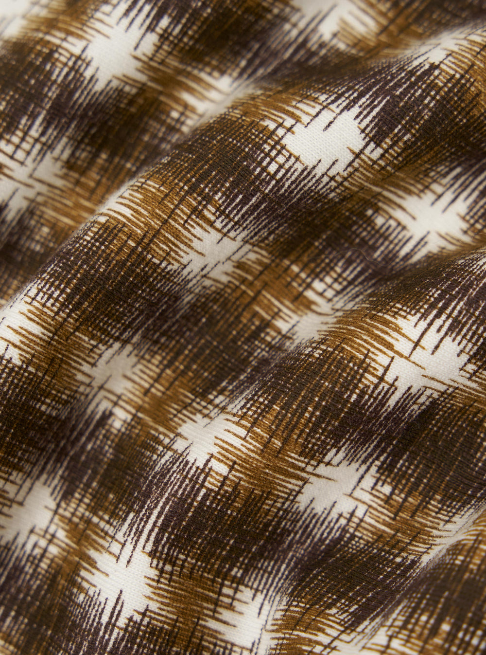 A close-up fabric swatch of the Brown Sound Wave Jersey Vacation Polo showcases a detailed textured pattern. The jersey fabric features a wavy, rippled design in shades of brown and tan, creating a visual effect similar to a sound wave or a zig-zag stripe.
