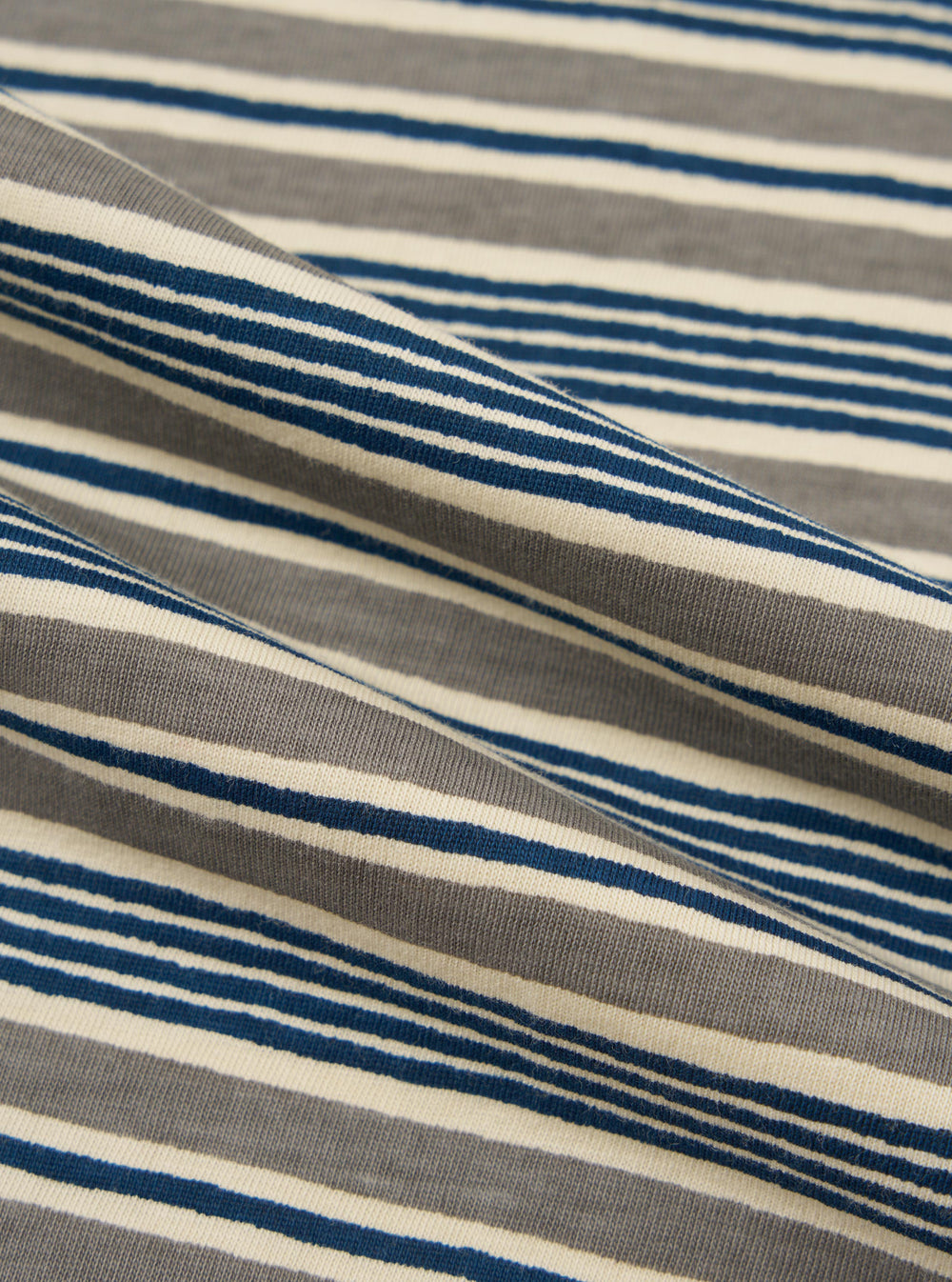 A close-up fabric swatch of the Grey OS Stripe Jersey Vacation Polo shows a detailed view of the light grey and white horizontal striped pattern. The image focuses on the soft, textured cotton jersey material.