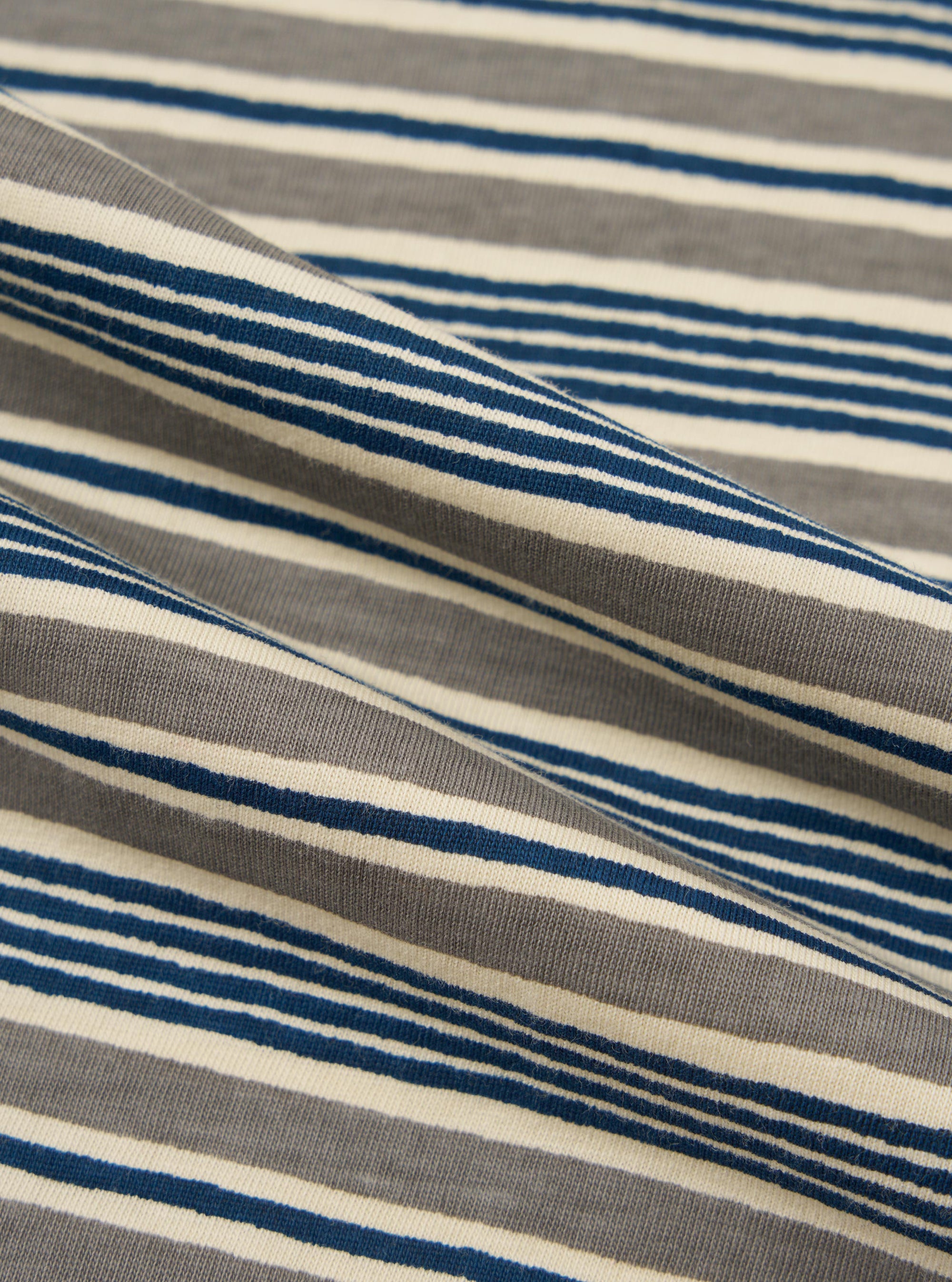 A close-up fabric swatch of the Grey OS Stripe Jersey Vacation Polo shows a detailed view of the light grey and white horizontal striped pattern. The image focuses on the soft, textured cotton jersey material.