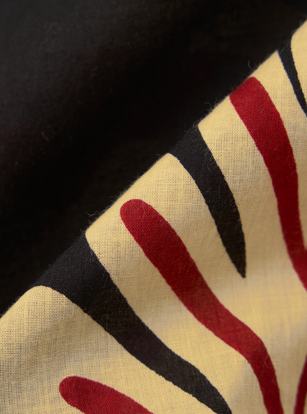 A close-up fabric swatch of the Black Baja Print Road Shirt features a detailed view of the 100% cotton material. The fabric has an all-over intricate patterned print in shades of black, grey, and white. The image focuses on the texture of the weave and the complexity of the print design.