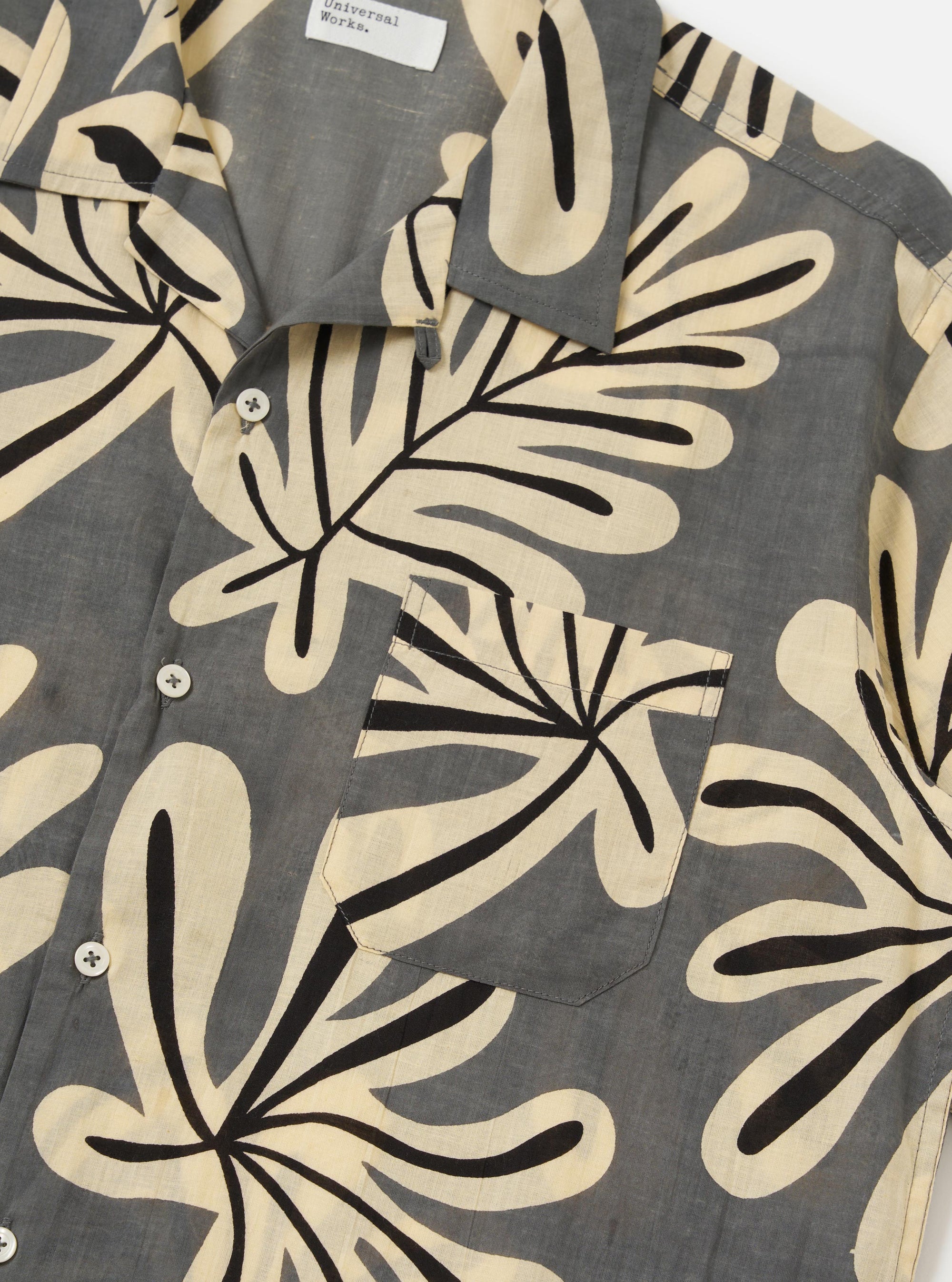 The Grey Baja Print Road Shirt is shown from a rear perspective, laid flat against a plain white background. The image highlights the short-sleeve construction, a straight hem, and the detailed botanical print across the grey cotton fabric.