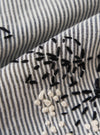 A square fabric swatch of the Grey Hand Embroidered Stripe Cotton Road Shirt shows a detailed close-up of the grey and white vertical striped fabric. Intricate hand-stitched floral embroidery in a darker thread is scattered across the material, highlighting the tactile texture of the cotton.
