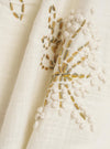 A close-up fabric swatch of the Ecru Hand Embroidered Cotton Road Shirt shows a detailed view of the lightweight cream-colored fabric. The material features vertical stripes and intricate, dark-colored hand-embroidered floral or geometric motifs. The image focuses solely on the texture and pattern of the garment.
