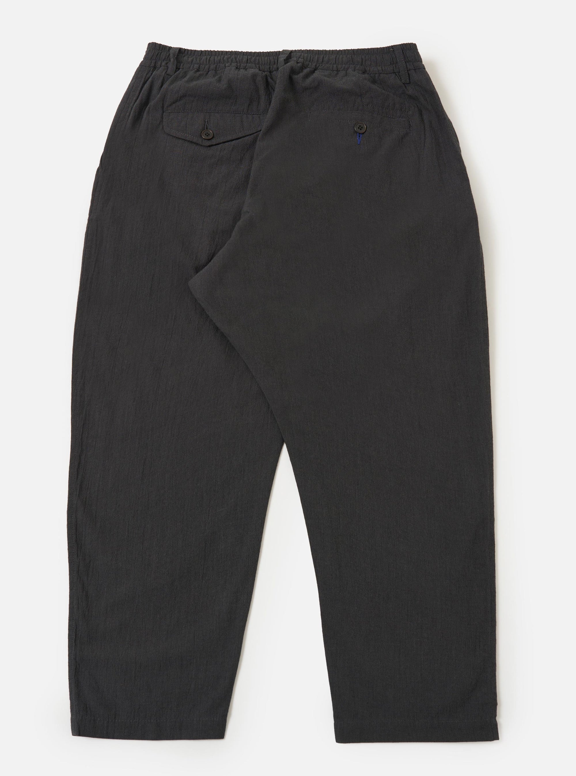 The back of the Charcoal Seattle Cotton Pleated Track Pant is displayed flat against a plain white background. The image shows the elasticated waistband with a drawstring, two rear pockets (one with a buttoned flap and one jetted), and a tapered leg.