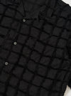 The Black 3D Check Road Shirt is shown from a rear perspective, laid flat against a solid white background. The image highlights the short sleeves, straight hem, and the unique textured, tufted surface of the black 3D check cotton fabric.