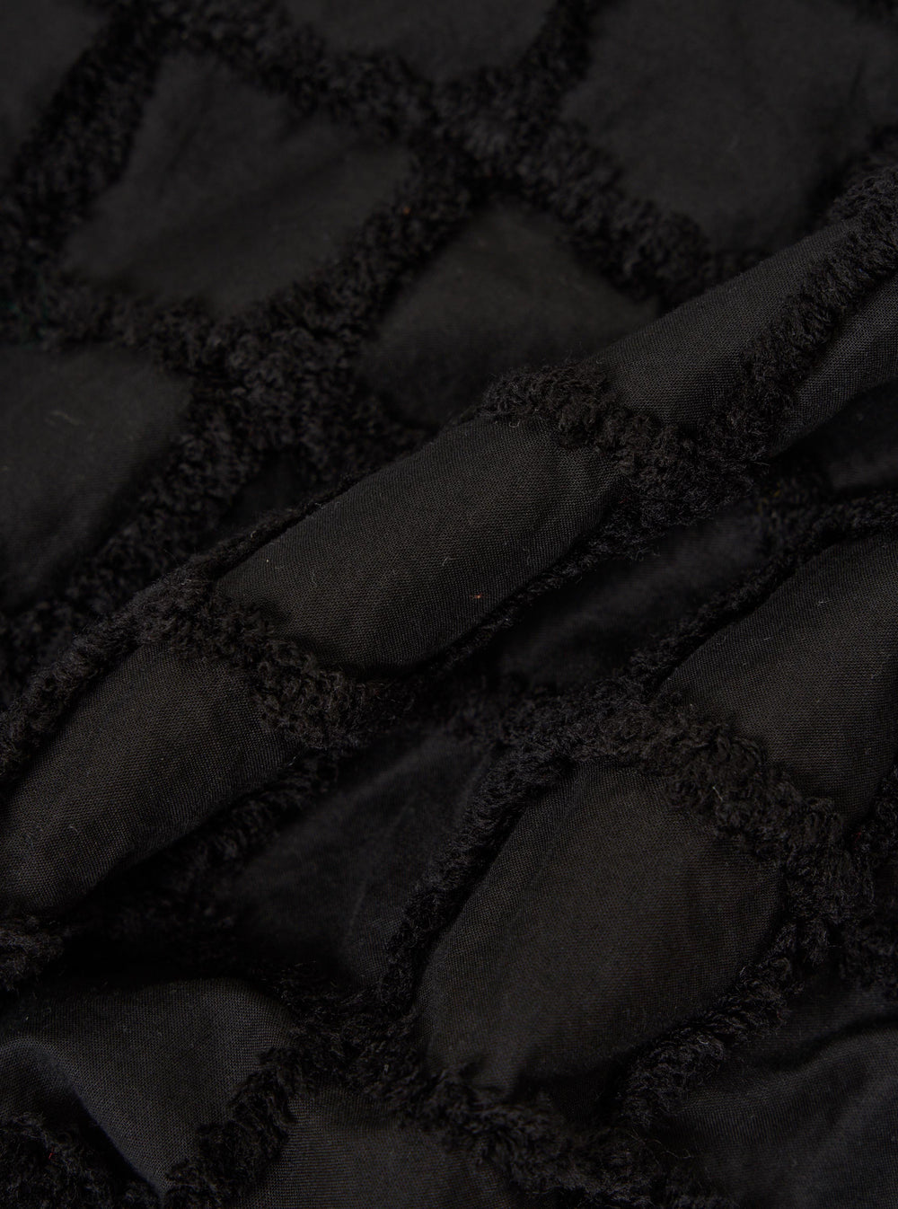 A close-up fabric swatch of the Black 3D Check Road Shirt showcases a textured, three-dimensional woven pattern in black and dark grey. The image focuses on the intricate grid-like structure of the cotton fabric.
