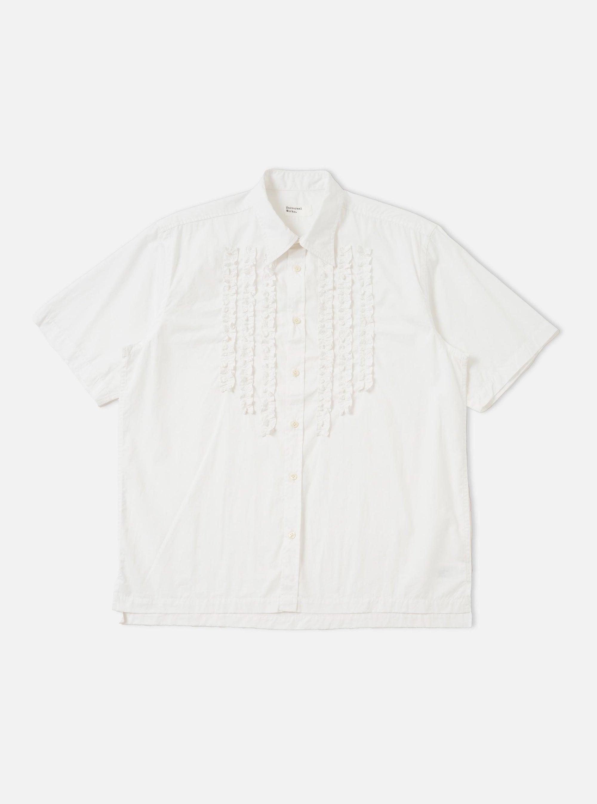 A White Poplin Frill Shirt is shown laid flat against a solid white background. The garment features a classic pointed collar, a full button-down front, and a vertical ruffled frill detail running alongside the central placket. The long sleeves are laid out to the sides, and the hem is straight.