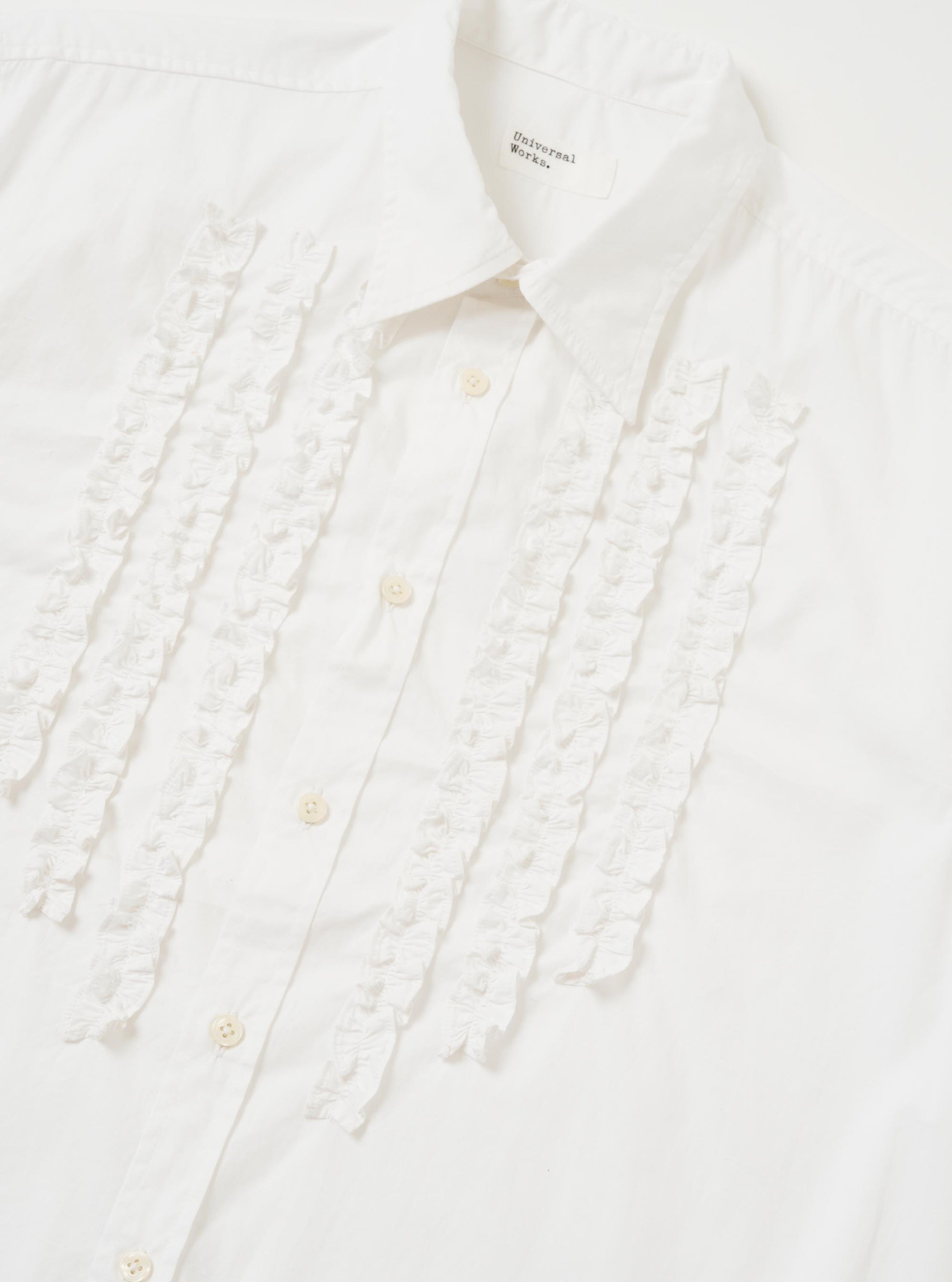 The White Poplin Frill Shirt is shown from a rear perspective, laid flat against a solid white background. The image highlights the back yoke and the straight-cut hem of the garment.