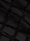A detailed, close-up fabric swatch of the Black 3D Check Windcheater Jacket highlights a textured cotton material with a three-dimensional grid or checkered pattern in black and dark grey. The image focuses solely on the intricate weave and tonal contrast of the fabric.