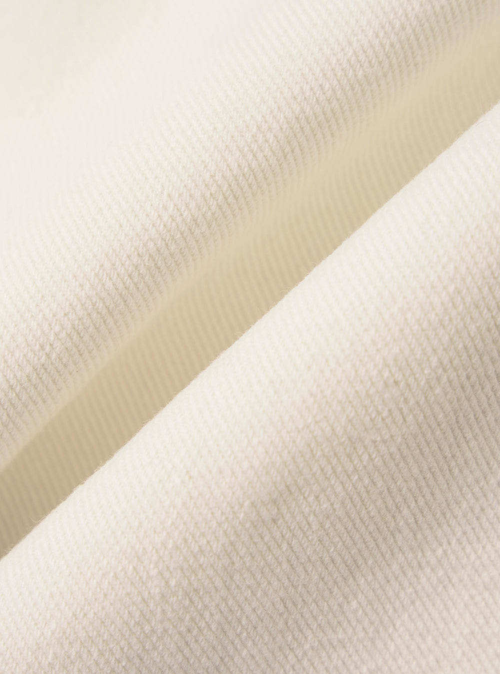 A detailed, close-up fabric swatch of the Ecru Slub Drill material used for the Dutch Pant. The image highlights the off-white, unbleached color and the distinct, textured slub weave of the cotton fabric.