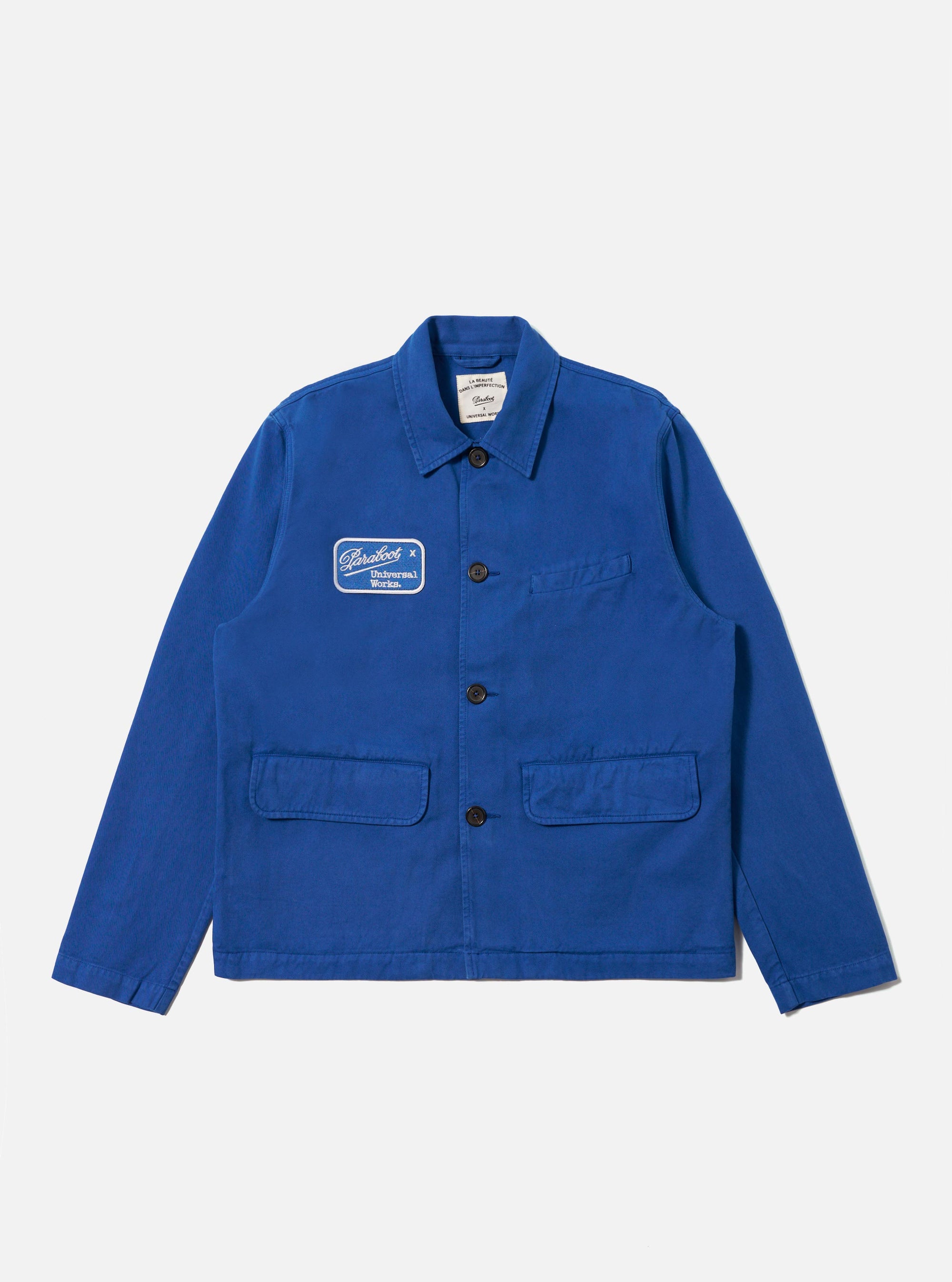 The Paraboot x Universal Works Navy Derek Twill Warmus Jacket is displayed on a white background. The jacket is navy twill with a patch on the chest.