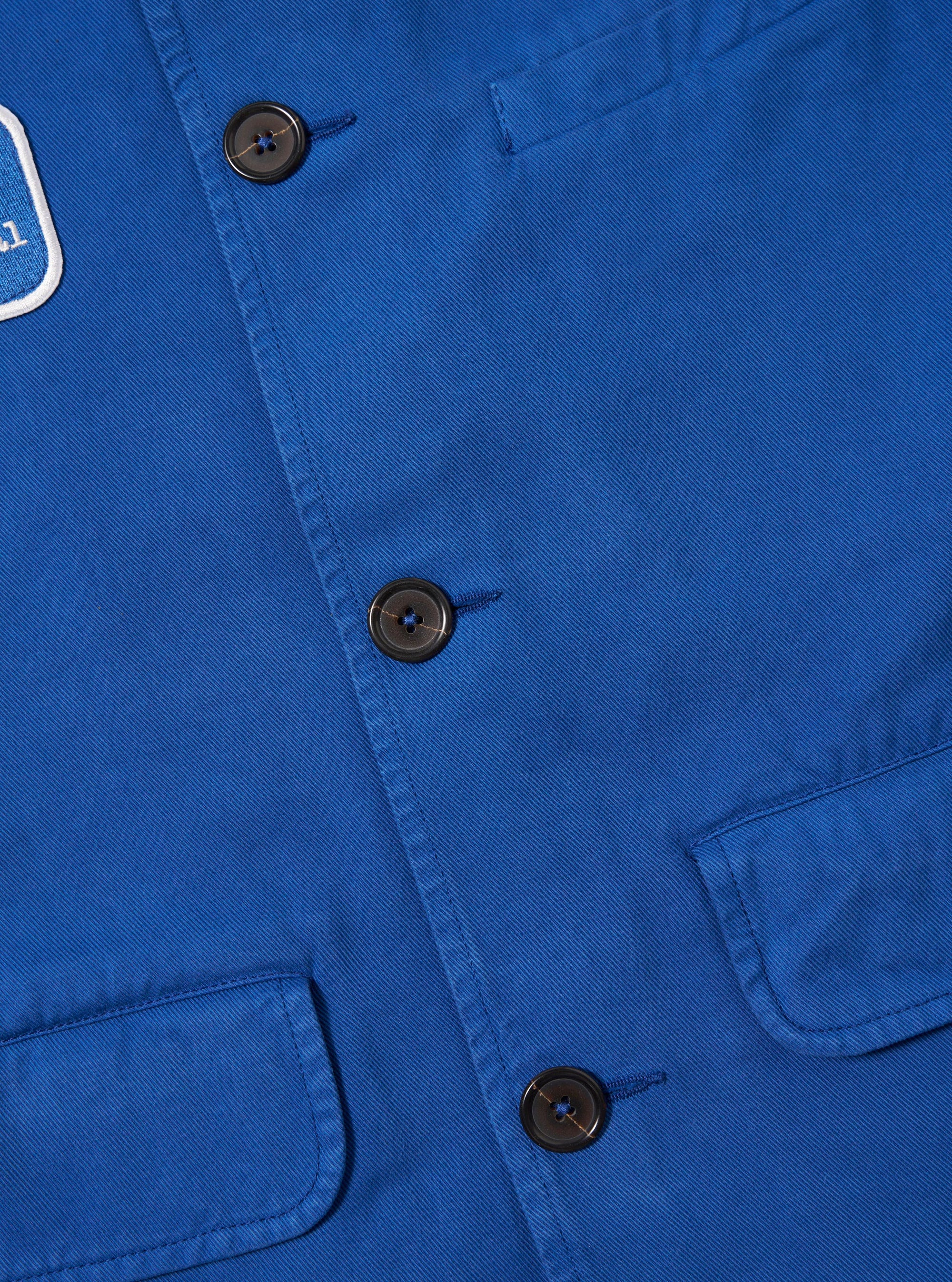 Close-up of the Paraboot x Universal Works Navy Derek Twill Warmus Jacket. Features include a navy twill material, button closure, and chest pockets. 