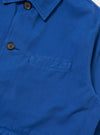 Close-up of the Paraboot x Universal Works Navy Derek Twill Warmus Jacket. Shows the blue twill fabric, brown buttons, and pocket detail against a plain white background.