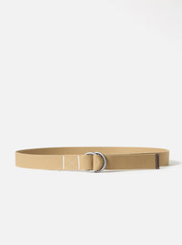 The Sand Canvas Webbing O Ring Belt is shown as a flat lay against a white background. The belt is made from a light beige canvas webbing and features two silver-toned O-ring buckles at one end. The end of the belt is finished with a brown leather trim.