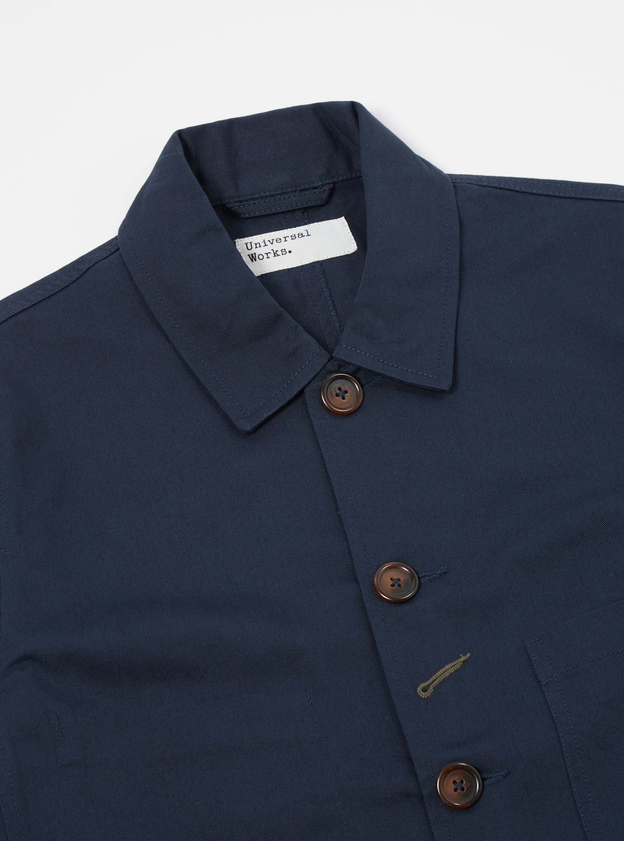 Close-up of the Navy Twill Bakers Jacket on a white background. The jacket is navy blue with brown buttons. The twill fabric has a subtle texture.