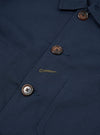 Close-up of the navy twill Bakers Jacket, showcasing the fabric texture, button details, and pocket stitching. The jacket is neatly arranged on a flat surface.