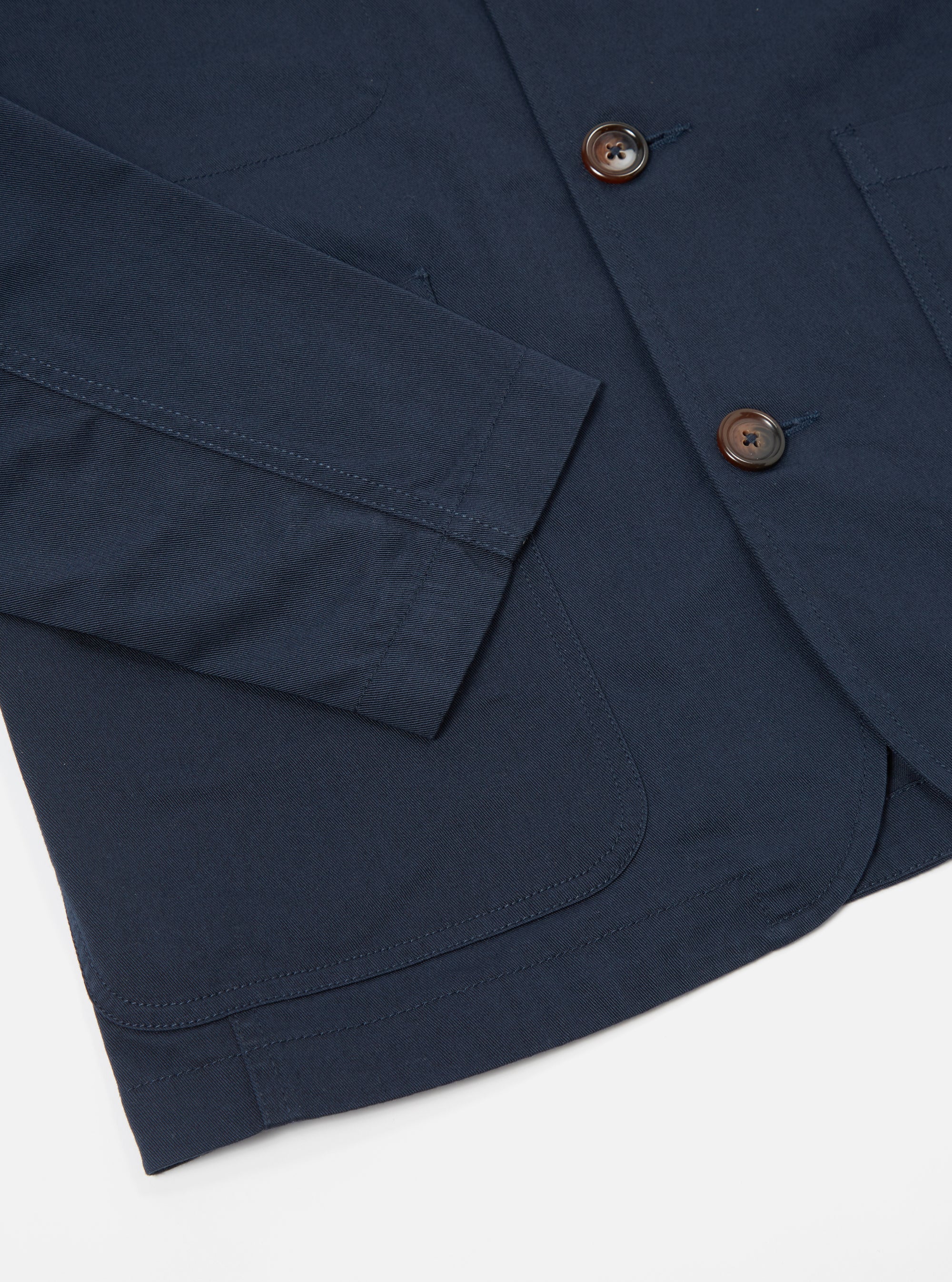 Close-up of the navy twill Bakers Jacket on a white background. Shows the jacket's texture, buttons, pockets, and sleeve.
