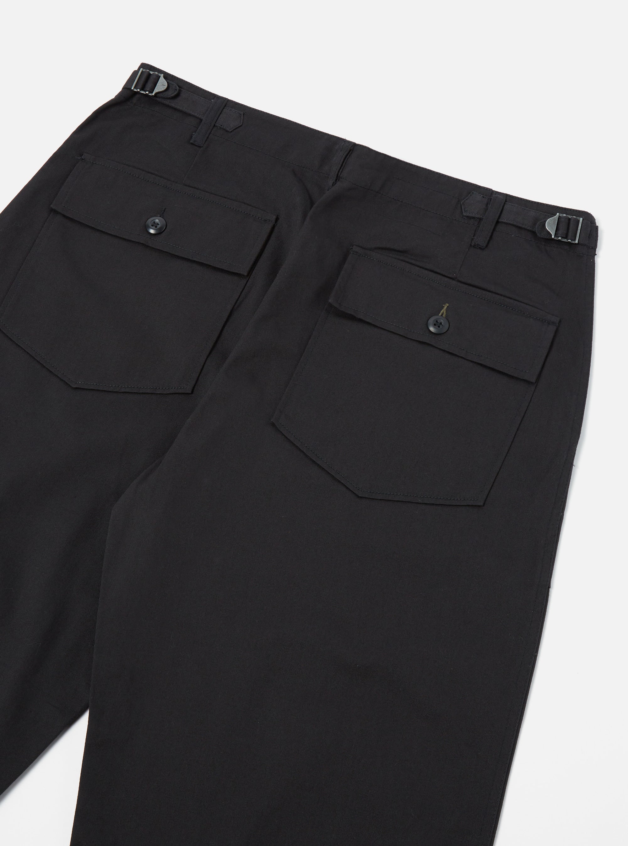Close-up of the back of the Black Twill Fatigue Pant (Undarted) on a white background. The black twill fabric shows two buttoned pockets and adjustable waist tabs.