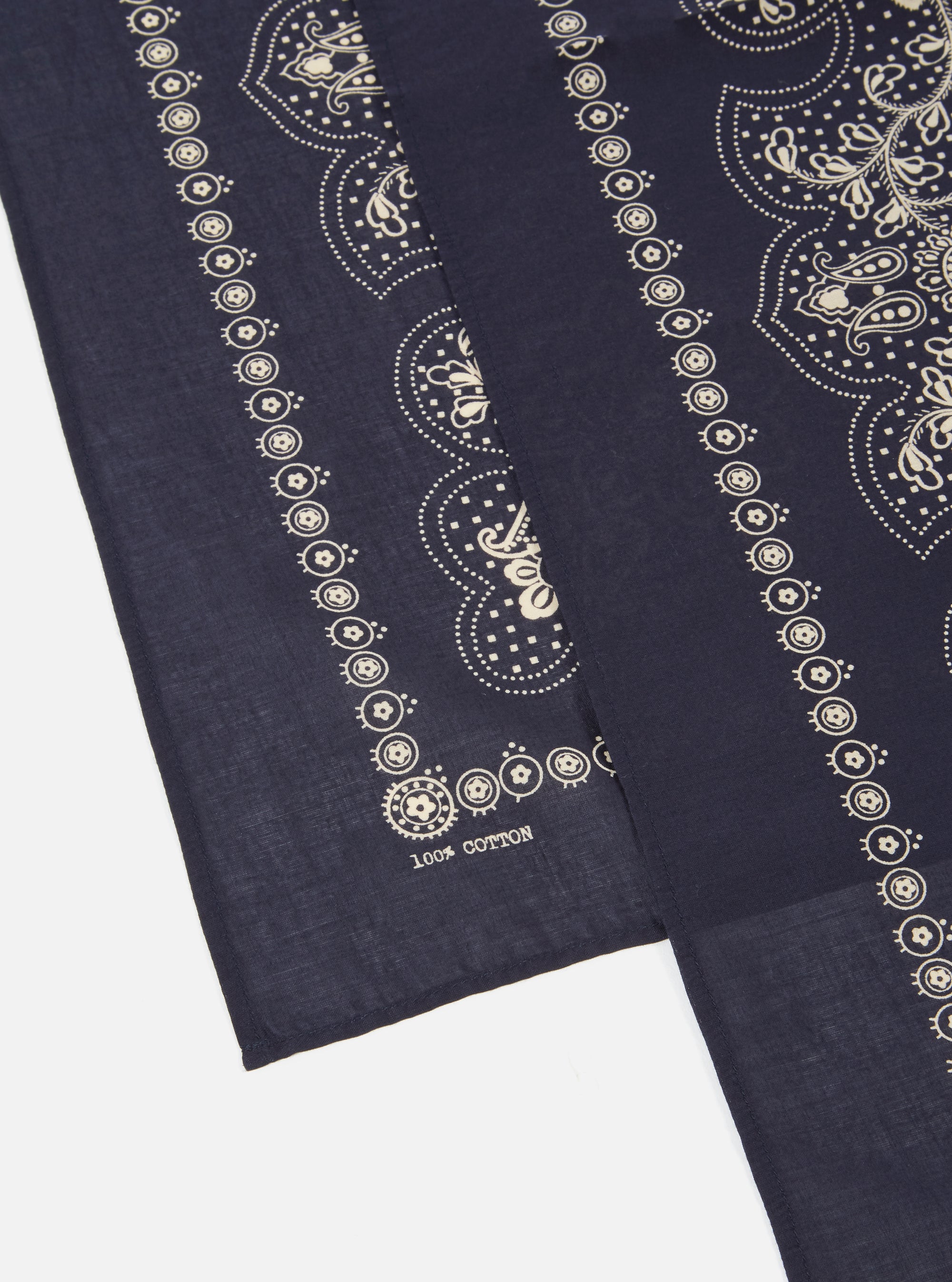 Close-up of a Navy Classic Bandana Neckerchief on a white surface. The 100% cotton bandana has a detailed paisley pattern in cream.