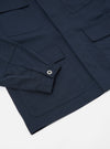 Close-up of the Navy Twill MW Fatigue Jacket on a white surface. The jacket features a buttoned sleeve and multiple pockets.