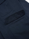 Close up of the Navy Twill MW Fatigue Jacket showing the twill fabric and pocket detail. The jacket is laid on a white surface.