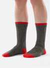 Close-up of a person wearing Derby Wool Hike Sock on a white background. The sock is gray with a red toe and cuff.