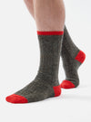 Close-up of a person wearing Derby Wool Hike Sock, a gray wool sock with red toe and trim, on a white background.