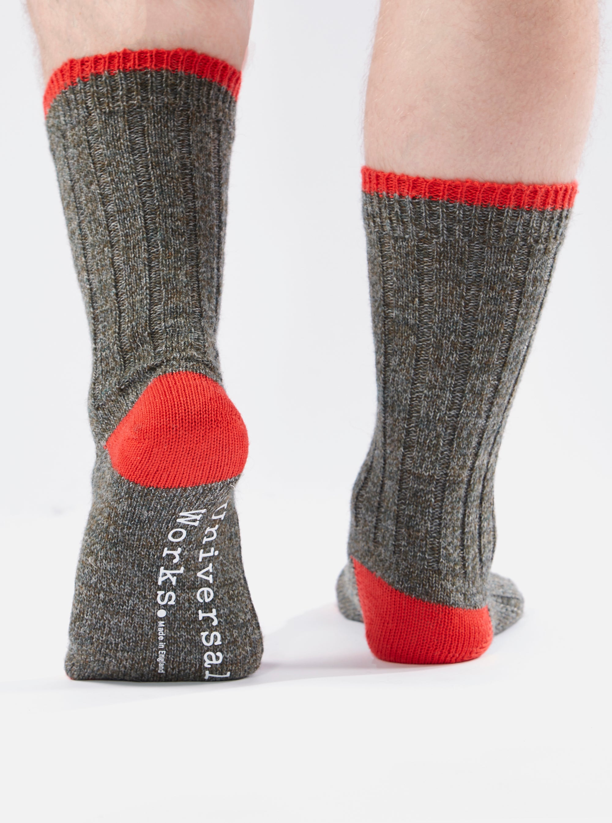 Close-up of the back of two legs wearing Derby Wool Hike Sock. The socks are gray with red heels and tops. The background is white.